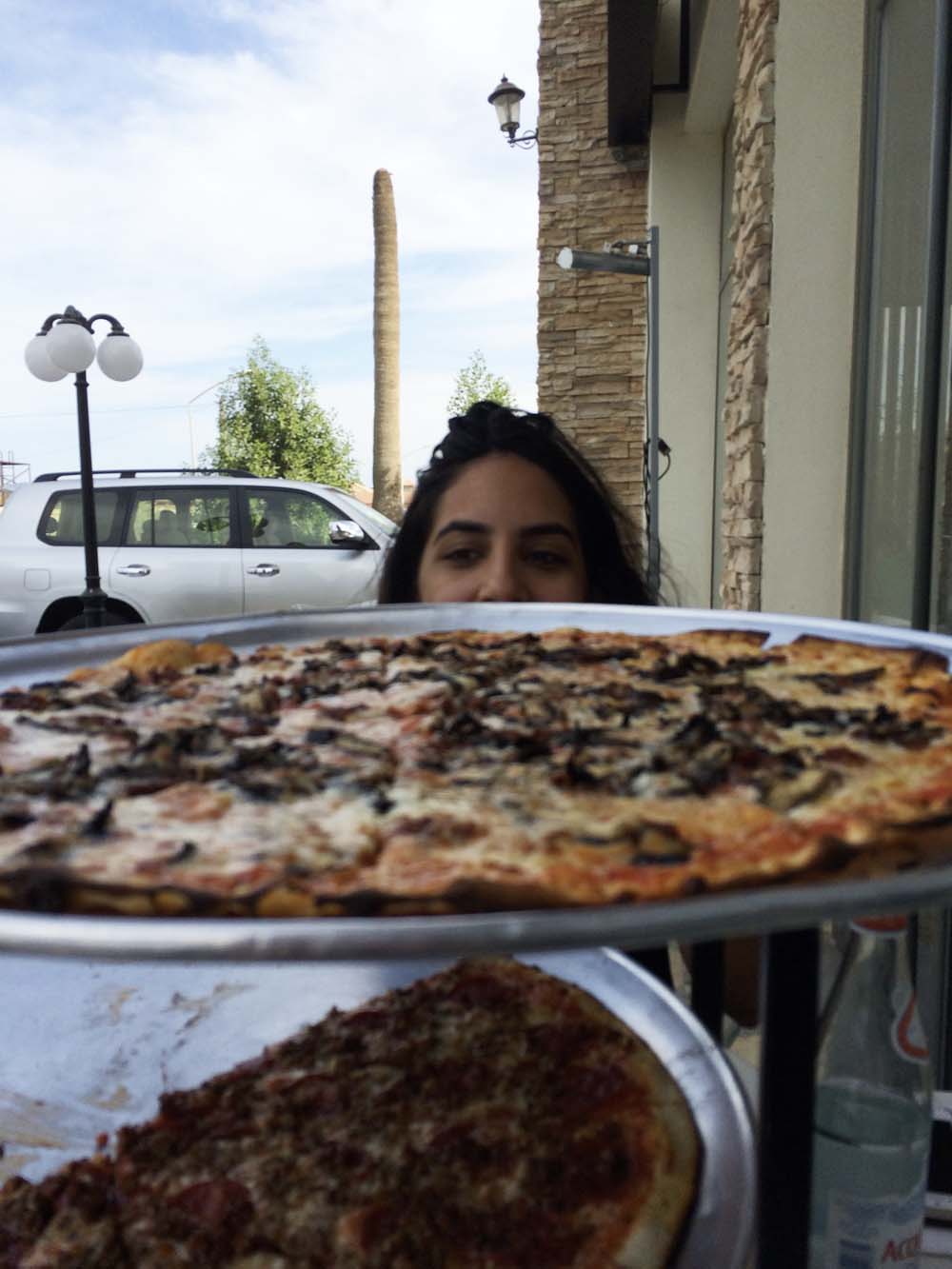 my view at lunch: yasmine, two giant pizzas, and a frondless palm 